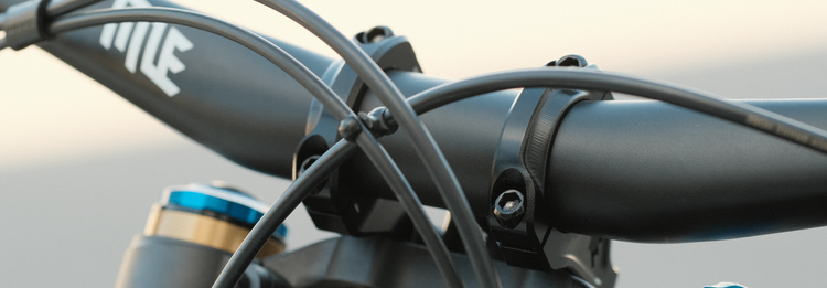 Close-up of a bicycle handlebar with black and blue components on a blurred background