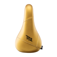 Gold bicycle seat with 'TITLE' branding on a white background