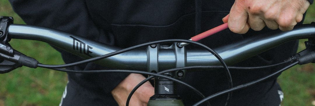 Close-up of a person adjusting a bicycle handlebar with a pink tool.