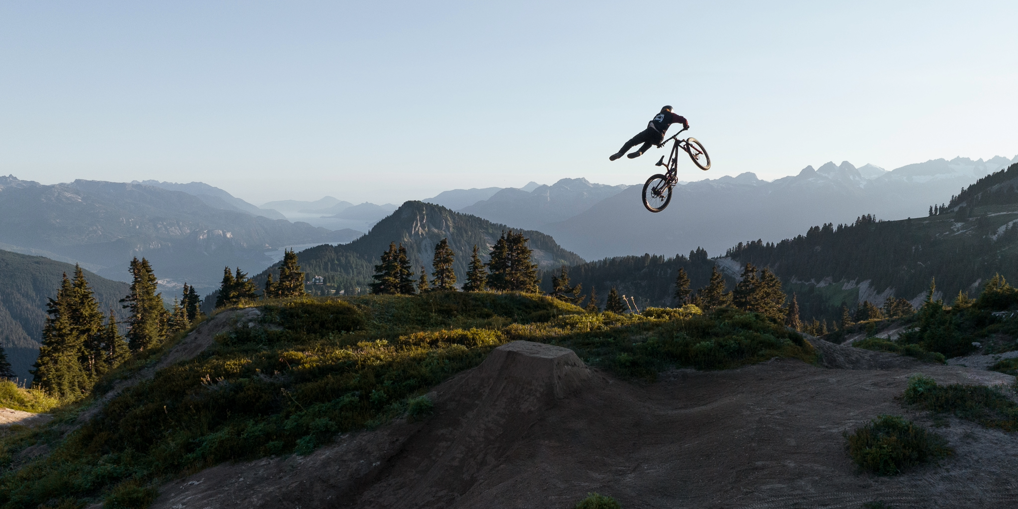 Person on a bicycle performing a jump with mountains in the background