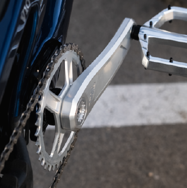 Close-up of a bicycle chain and gear system on a road.